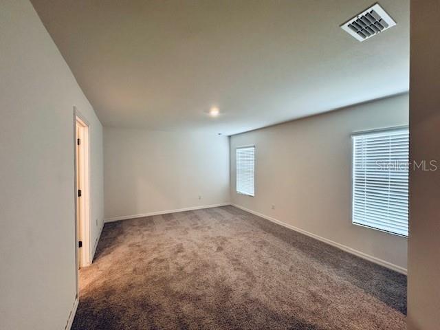 carpeted empty room featuring visible vents and baseboards