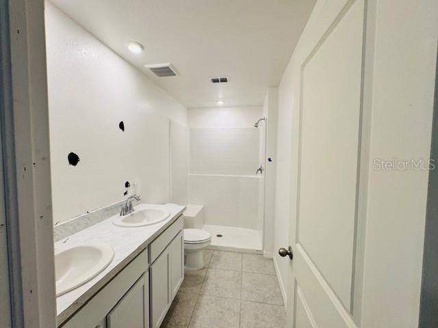 bathroom with vanity, toilet, a shower, and tile patterned flooring