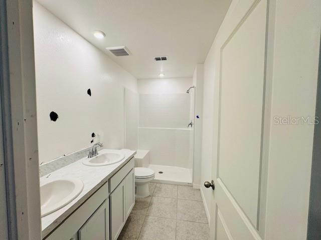 bathroom with a stall shower, a sink, and tile patterned floors