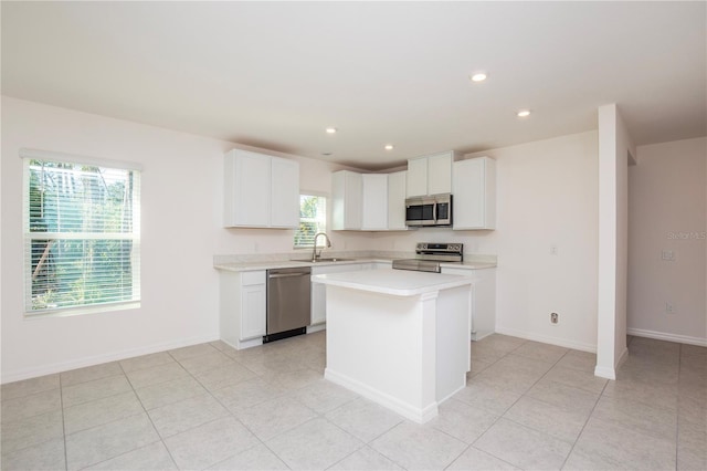 18059 Regan Ave, Port Charlotte, FL 33948 - kitchen featuring stainless steel appliances, light countertops, a sink, a kitchen island, and white cabinets