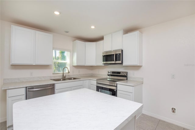 18059 Regan Ave, Port Charlotte, FL 33948 - kitchen with appliances with stainless steel finishes, a sink, baseboards, white cabinetry, and a center island