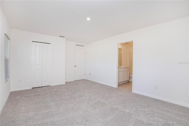 18059 Regan Ave, Port Charlotte, FL 33948 - unfurnished bedroom with light colored carpet, baseboards, recessed lighting, ensuite bathroom, and a closet