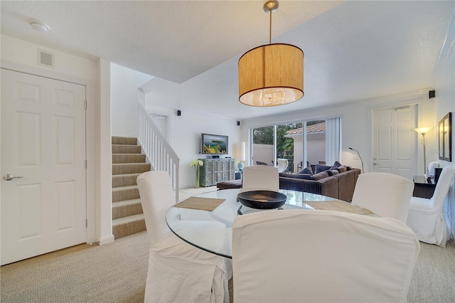 carpeted dining area with a textured ceiling