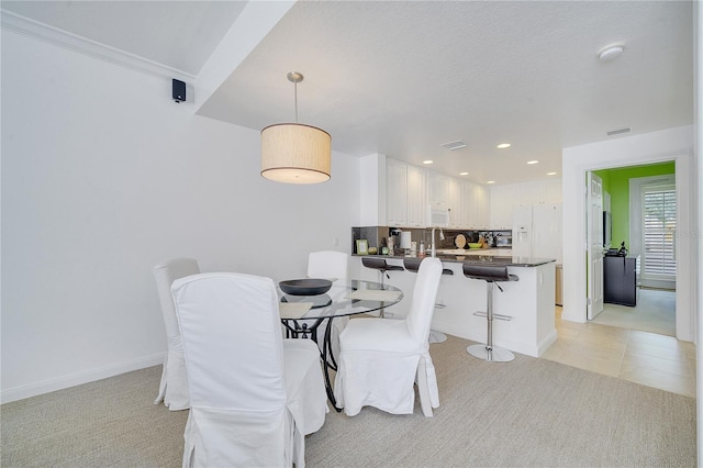 carpeted dining area with a textured ceiling and sink