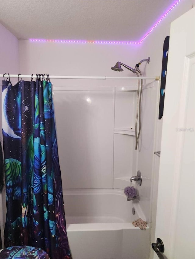 bathroom with a textured ceiling and shower / tub combo with curtain