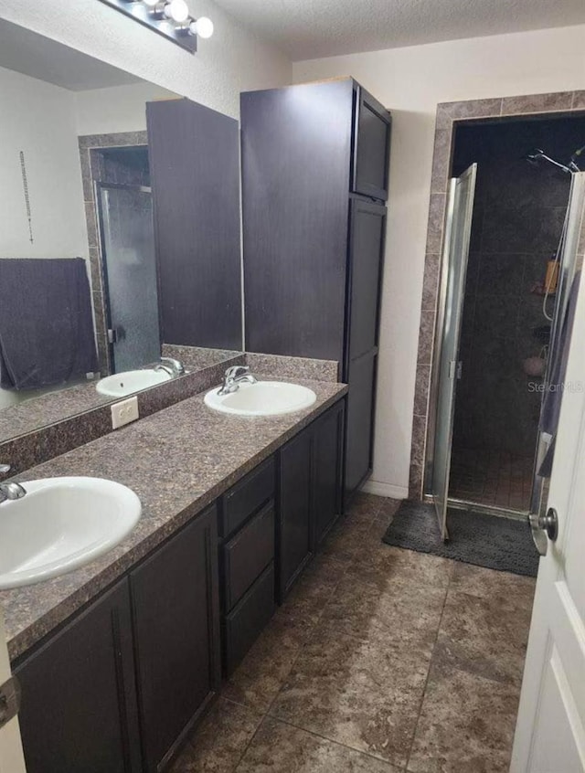 bathroom with walk in shower, vanity, and a textured ceiling