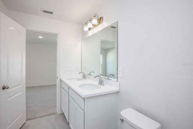 bathroom with double sink vanity, toilet, and tile patterned floors