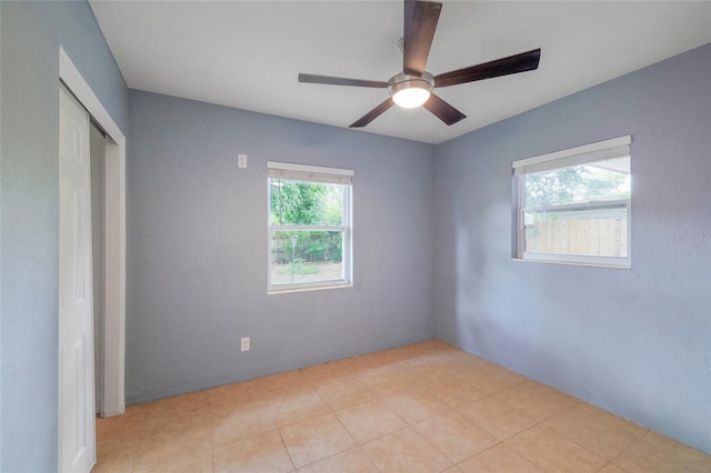 unfurnished bedroom with light tile patterned floors, ceiling fan, and a closet