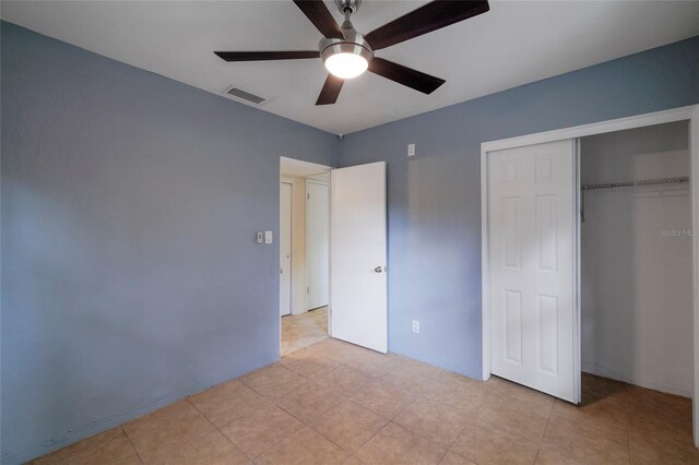 unfurnished bedroom with light tile patterned floors, ceiling fan, and a closet