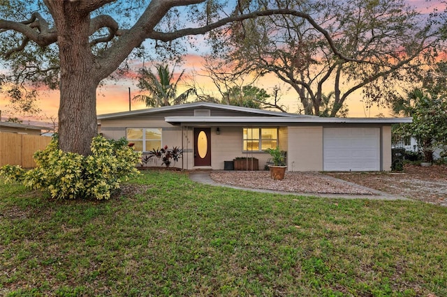 mid-century modern home with a garage, a yard, and fence