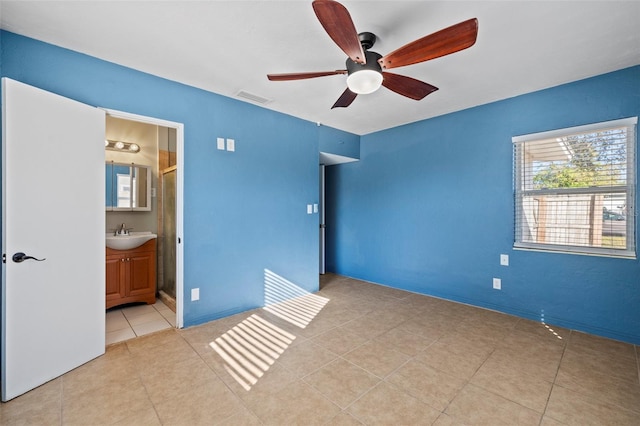 unfurnished bedroom featuring ceiling fan, light tile patterned flooring, a sink, visible vents, and ensuite bath