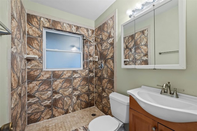 bathroom with tiled shower, vanity, and toilet