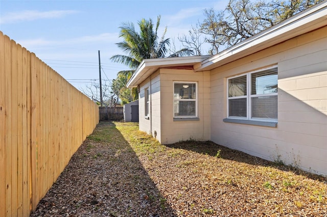 view of home's exterior with concrete block siding and a fenced backyard