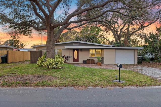 mid-century modern home with a garage, fence, driveway, and a front lawn