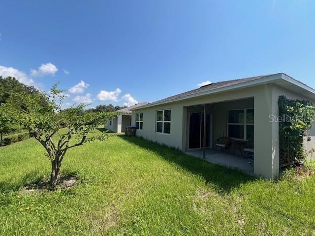 back of property with a yard and a patio