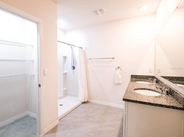 bathroom featuring tile patterned flooring, vanity, and walk in shower