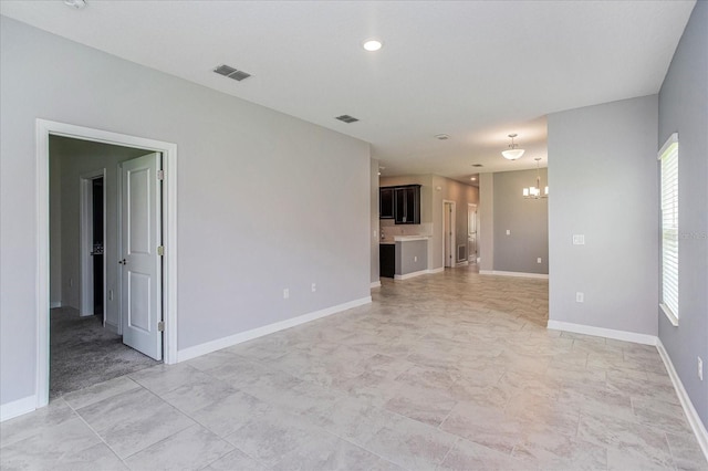 tiled spare room with a notable chandelier