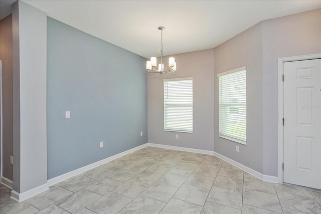 spare room with light tile patterned floors and an inviting chandelier