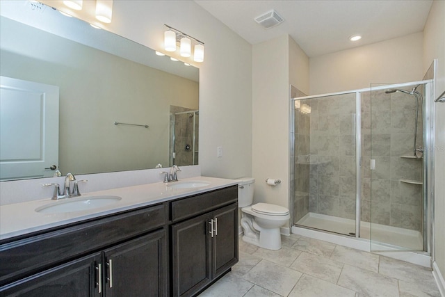 bathroom featuring a shower with shower door, double vanity, tile patterned flooring, and toilet