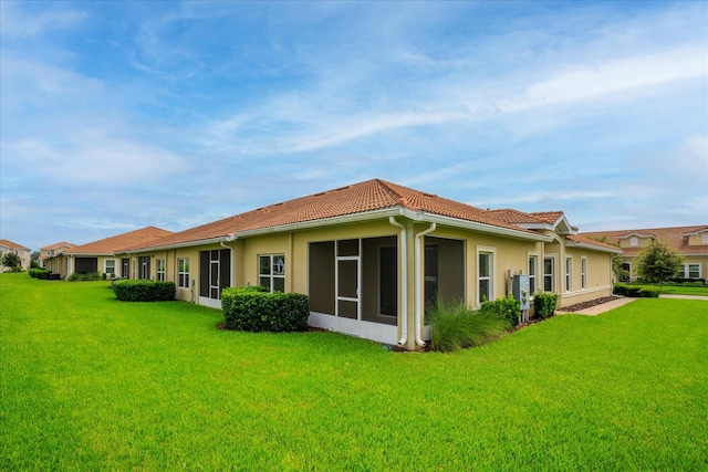 rear view of house featuring a lawn and a sunroom