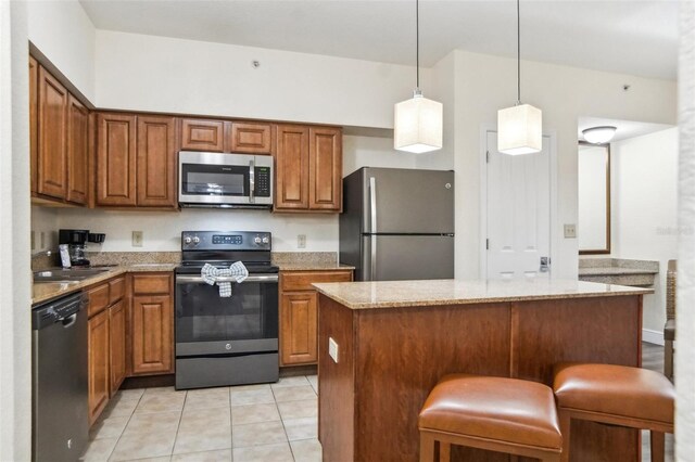 kitchen with a breakfast bar, light stone countertops, decorative light fixtures, light tile patterned flooring, and stainless steel appliances