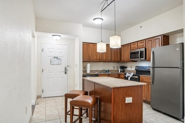 kitchen with a kitchen bar, light tile patterned floors, a kitchen island, stainless steel appliances, and hanging light fixtures