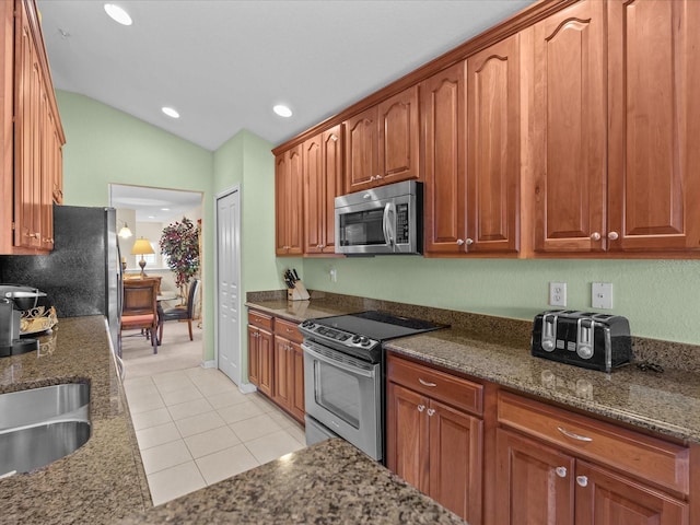 kitchen with stainless steel appliances, light colored carpet, vaulted ceiling, sink, and dark stone counters