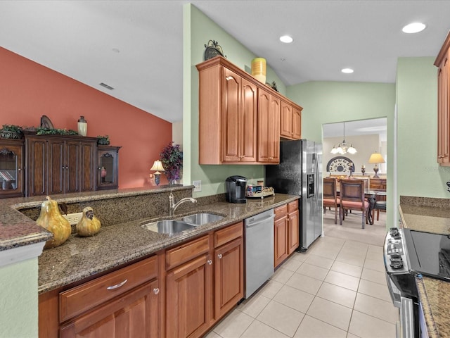 kitchen featuring appliances with stainless steel finishes, dark stone counters, light tile patterned floors, vaulted ceiling, and sink