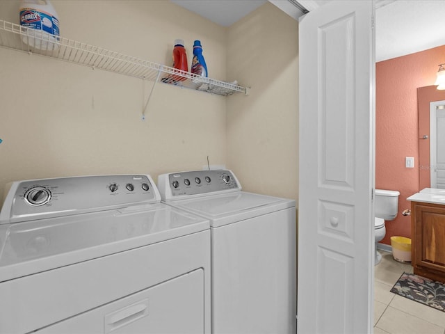 clothes washing area with light tile patterned floors and washer and dryer