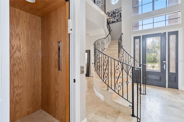 foyer with tile patterned floors, elevator, a high ceiling, and a healthy amount of sunlight