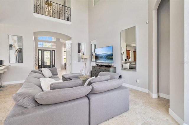 living room featuring light tile patterned floors, french doors, and a towering ceiling