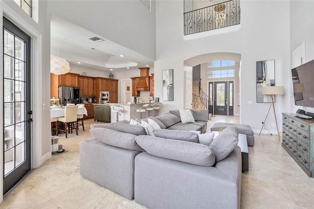 tiled living room with a towering ceiling and a raised ceiling