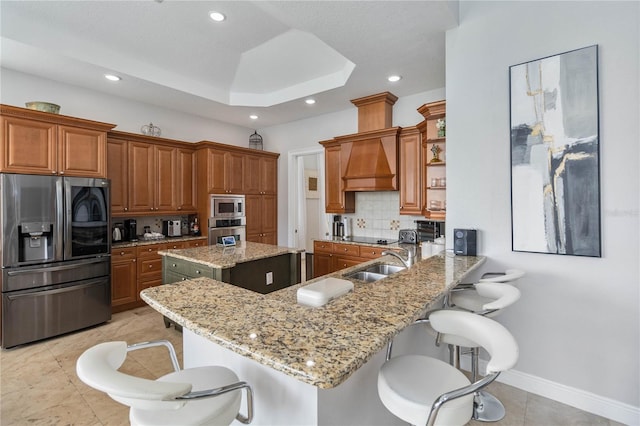 kitchen with appliances with stainless steel finishes, sink, custom range hood, light tile patterned flooring, and a kitchen island