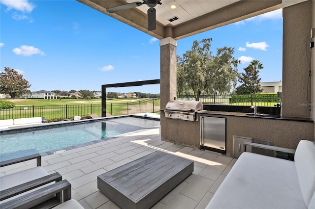 view of swimming pool featuring a grill, an outdoor kitchen, a patio, ceiling fan, and a yard