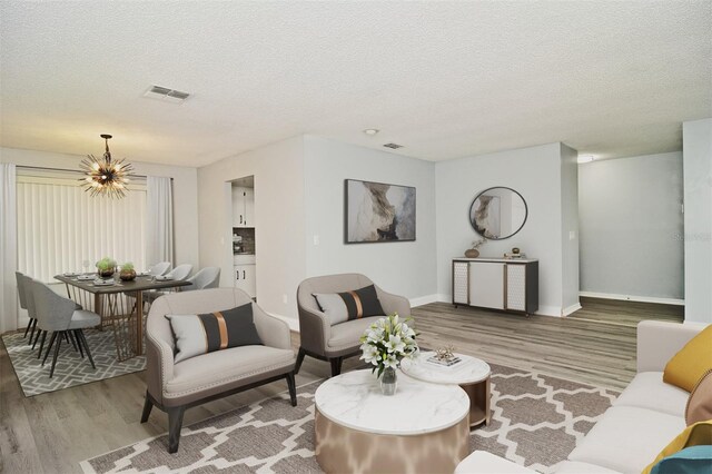 living room featuring light wood-type flooring, a textured ceiling, and a chandelier