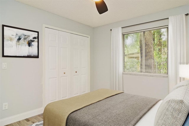 bedroom with a textured ceiling, hardwood / wood-style floors, ceiling fan, and a closet