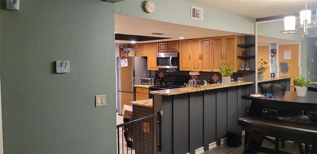 kitchen featuring a chandelier, kitchen peninsula, light stone countertops, decorative light fixtures, and stainless steel appliances