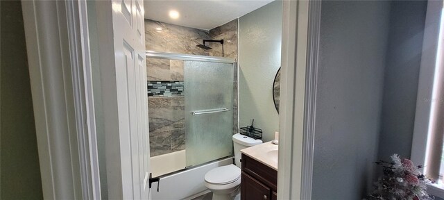 full bathroom with enclosed tub / shower combo, vanity, and toilet