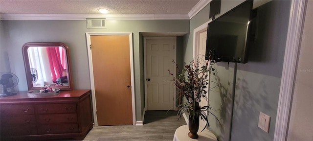 interior space featuring ornamental molding, a textured ceiling, and light hardwood / wood-style floors