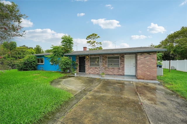 ranch-style home with cooling unit and a front lawn