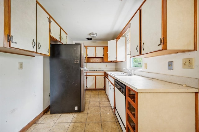 kitchen featuring white cabinetry, sink, light tile patterned floors, and stainless steel fridge