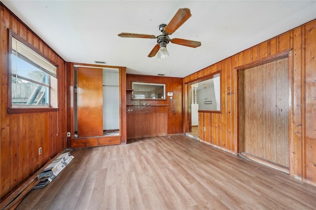 spare room featuring wooden walls, light hardwood / wood-style floors, and ceiling fan