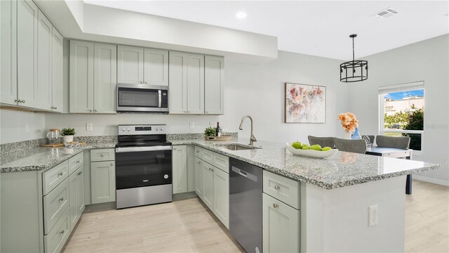 kitchen featuring stainless steel appliances, kitchen peninsula, and light hardwood / wood-style floors