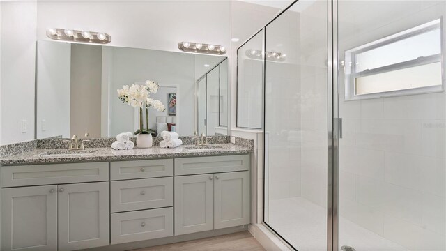 bathroom with a shower with shower door, wood-type flooring, and double vanity