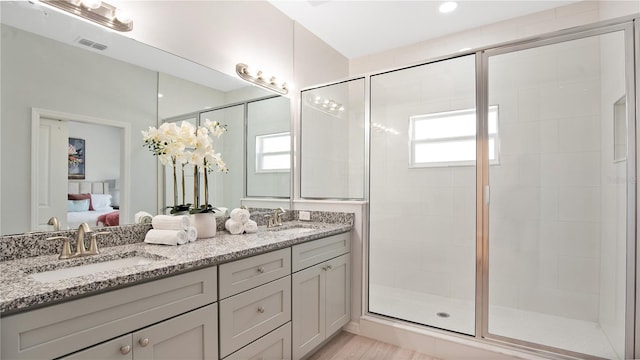 bathroom with an enclosed shower, double sink vanity, a healthy amount of sunlight, and hardwood / wood-style flooring