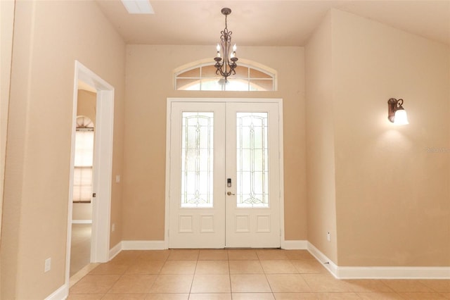 tiled entryway featuring french doors and a chandelier