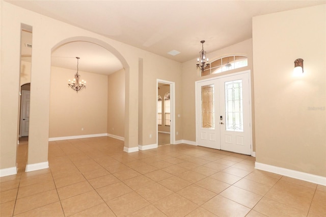 tiled foyer featuring french doors, a healthy amount of sunlight, and a notable chandelier