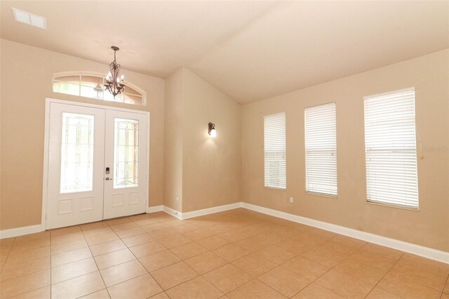 foyer with vaulted ceiling, a notable chandelier, light tile patterned floors, and french doors