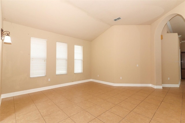 tiled spare room featuring vaulted ceiling