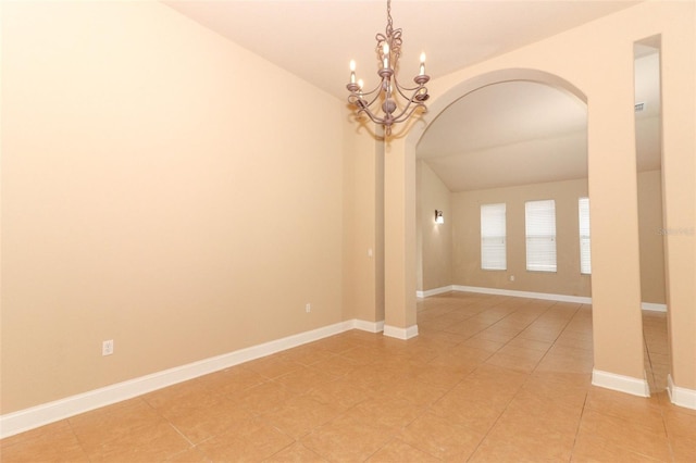 tiled empty room with lofted ceiling and a chandelier